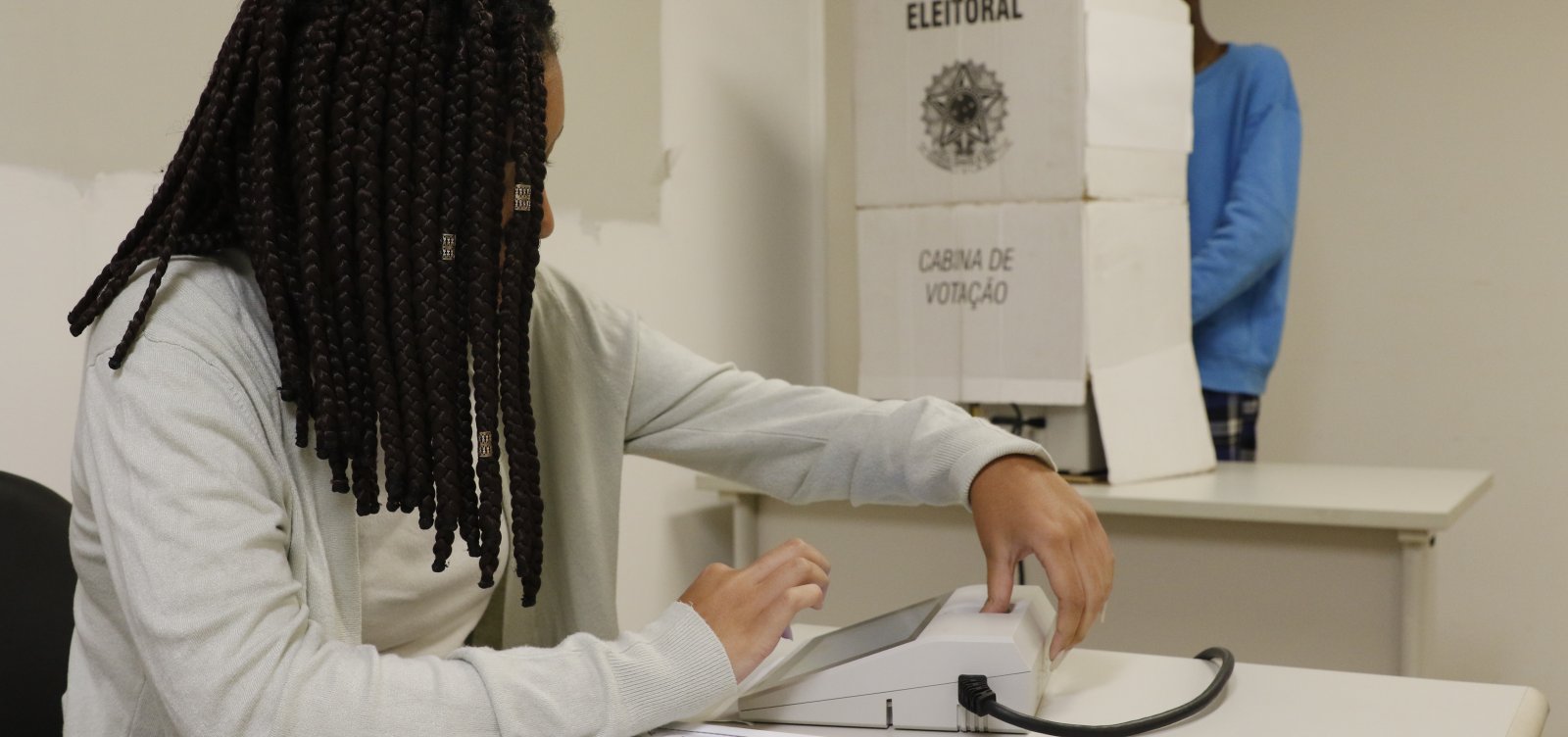 Eleitora utiliza urna eletrônica em seção de votação.